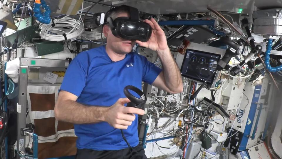 Ein Astronaut mit einem Virtual-Reality-Headset in einem überfüllten Raumstationsmodul