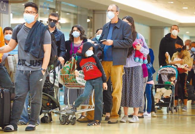 新冠肺炎疫情全球發燒，導致國際航班大亂，在第二航廈入境管制區內，一群外籍旅客正排隊準備轉機。（范揚光攝）