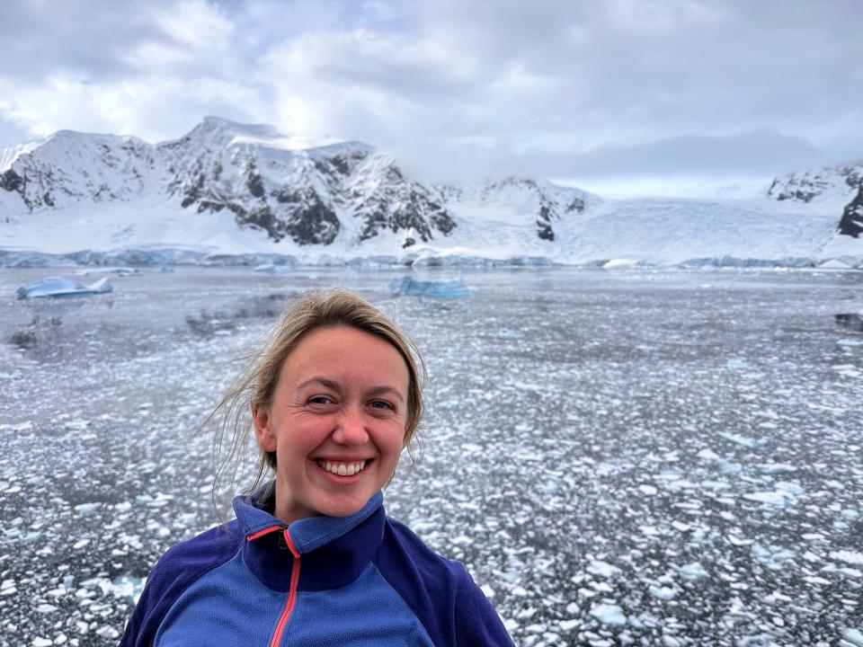 Alex smiling in front of icy water and snow-covered mountains.