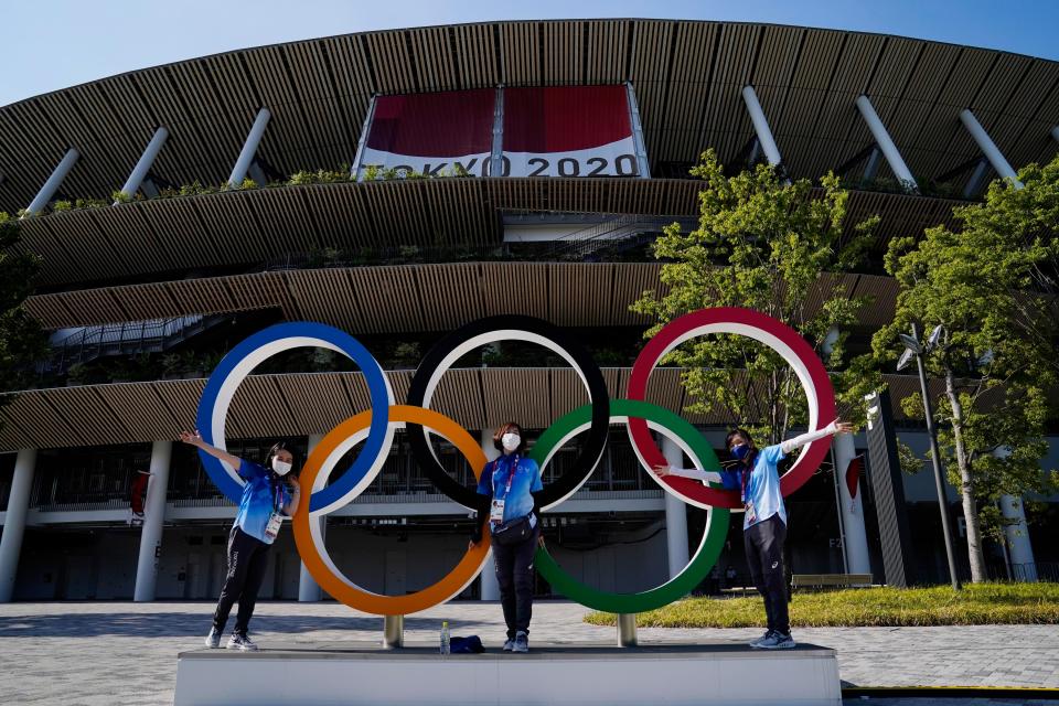 Volunteers pose with the Olympic rings during the opening ceremony for the Tokyo 2020 Olympic Summer Games at Olympic Stadium.