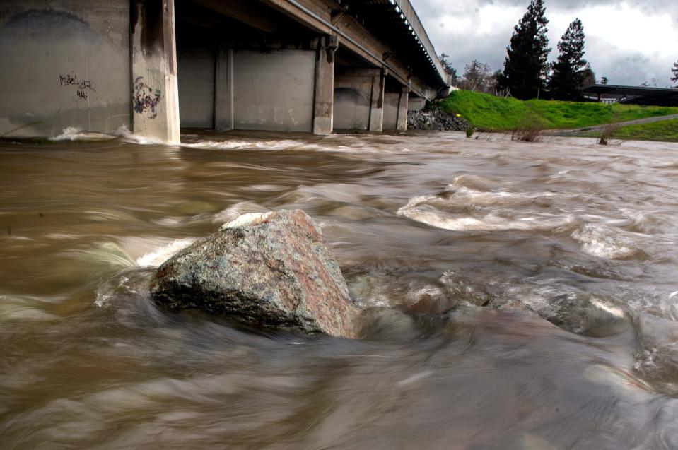 The storm-fed waters rise turning the normally placid Calaveras River into rapids near the Pacific Avenue bridge  in Stockton on Tuesday, March 14, 2023.
