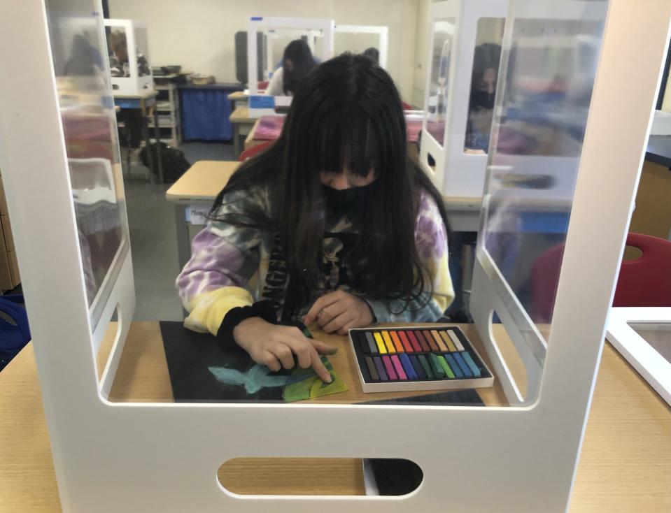 A student works on an art project while surrounded by plexiglass during class at the Sinaloa Middle School in Novato, Calif. on Tuesday, March 2, 2021. The school just reopened Monday, Feb. 22, 2021 for in-person learning. (AP Photo/Haven Daily)