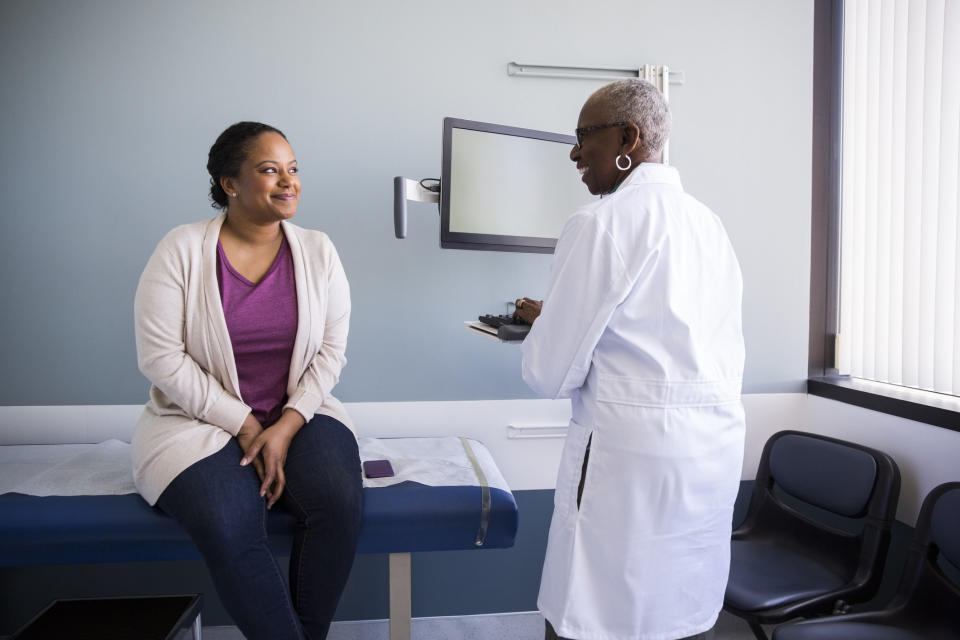 Smiling senior doctor talking to female patient in hospital