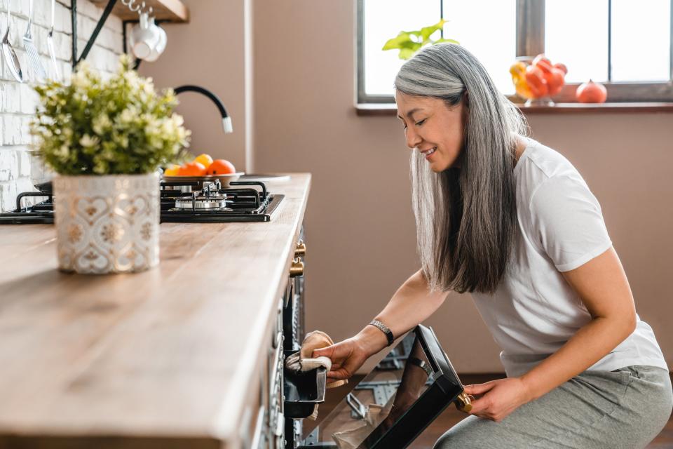 Mature beautiful caucasian woman baking in the oven in the kitchen