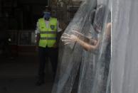 A woman wearing a protective face mask walks through a decontamination chamber as a preventive measure against the spread of the new coronavirus in the neighborhood of Petare in Caracas, Venezuela, Wednesday, July 15, 2020. (AP Photo/Ariana Cubillos)