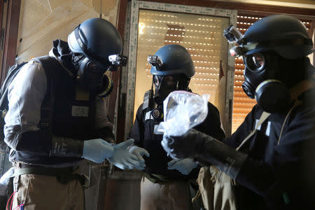 A United Nations (U.N.) chemical weapons expert, wearing a gas mask, holds a plastic bag containing samples from one of the sites of an alleged chemical weapons attack in the Ain Tarma neighbourhood of Damascus, Syria August 29, 2013. REUTERS/Mohamed Abdullah/Files