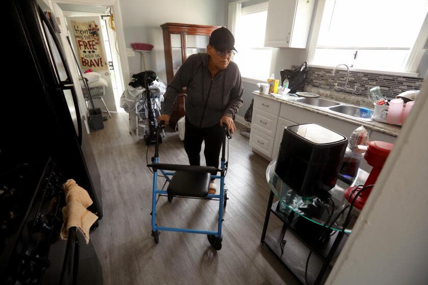 EL SERENO, CA - APRIL 5, 2024 - - Maria Merritt, 56, makes her way through the kitchen in the home she reclaimed on Sheffield Avenue in El Sereno on April 5, 2024. She starts using her walker midday due to residual pain from knee surgery. In March 2020, after seven decades of activism against a planned-then-abandoned freeway and at the start of a global health pandemic, Merritt and 11 other homeless and housing insecure individuals and families decided to seize empty, Caltrans-owned homes. They called themselves Reclaimers. For a two-year stretch, Merritt and the others lived in the homes legally after signing leases with the city housing authority. But those agreements have long since expired. Eviction lawsuits are proceeding in Los Angeles Superior Court, with trials scheduled for this spring. No matter the outcome, Merritt says she's not leaving again. (Genaro Molina/Los Angeles Times)