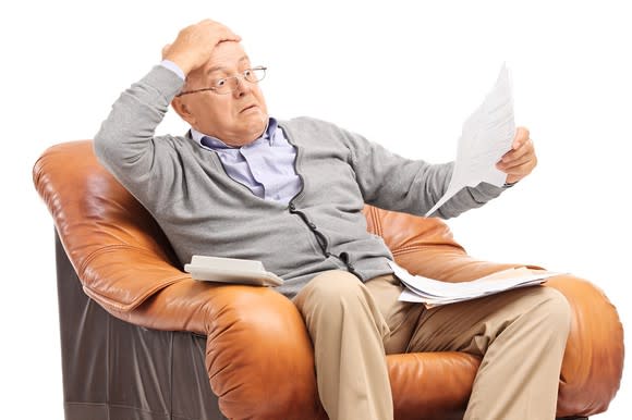 Older man looks at paper with stunned expression.