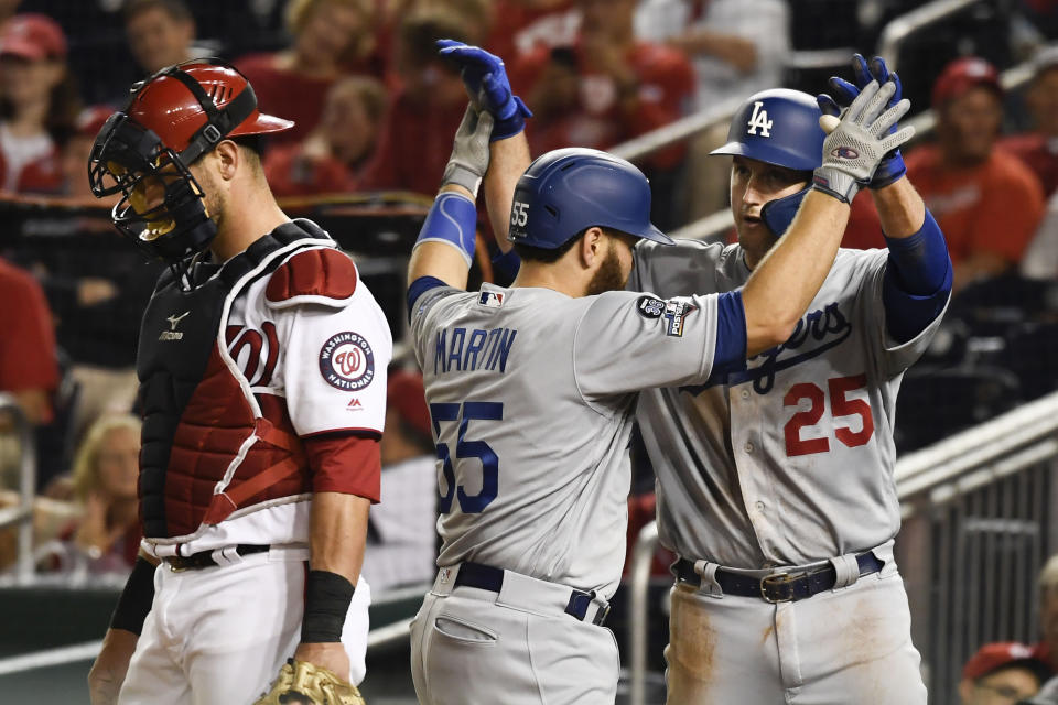 Los Angeles Dodgers' Russell Martin (55) celebrates with David Freese (25) after hitting a two-run home run off Washington Nationals relief pitcher Hunter Strickland during the ninth inning in Game 3 of a baseball National League Division Series on Sunday, Oct. 6, 2019, in Washington. At left is Nationals catcher Kurt Suzuki. (AP Photo/Susan Walsh)