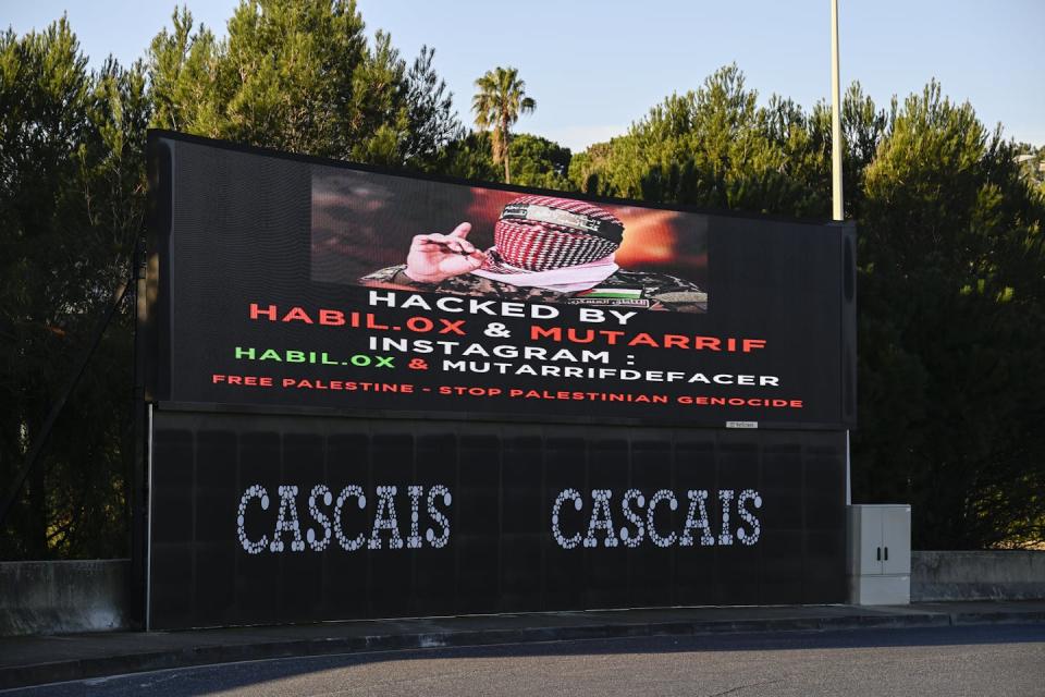 A billboard reads 'Hacked' and contains a pro-Palestinian message.