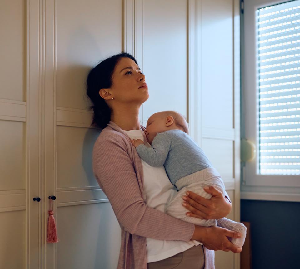 Mother holding baby looking sad. Posed by model. (Getty Images)