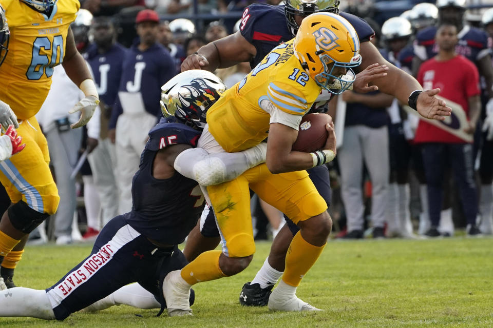 Southern University quarterback Glendon McDaniel (12) lunges forward for a first down while in the grasp of Jackson State linebacker Aubrey Miller Jr. (45) during the first half of the Southwestern Athletic Conference championship NCAA college football game Saturday, Dec. 3, 2022, in Jackson, Miss. (AP Photo/Rogelio V. Solis)