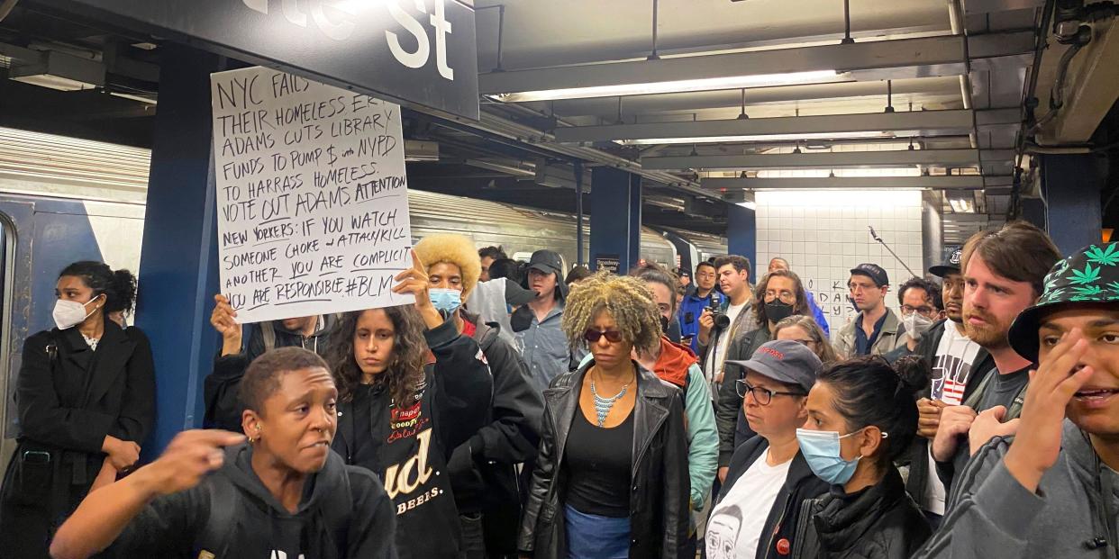 A group of protesters hold signs and march through a New York subway station.