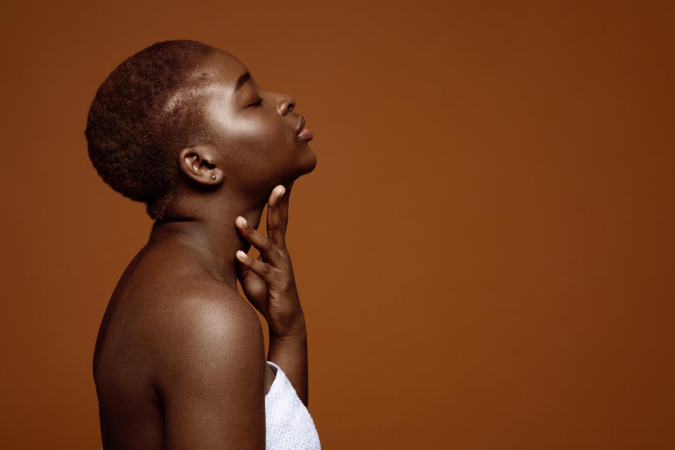 woman in a bath towel touching her neck