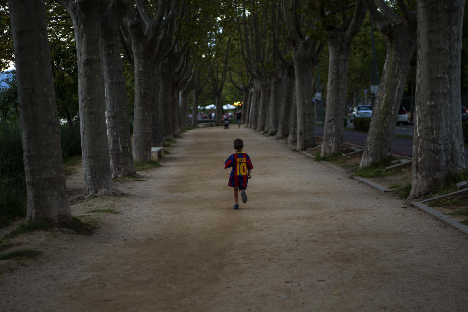 A boy wearing a shirt with the name of Barcelona soccer player Lionel Messi runs on a park in Banyoles, in Girona province, Spain on Wednesday, Sept. 2, 2020. Lionel Messi's future at Barcelona looked no closer to being resolved after the first meeting between the player's father and club officials on Wednesday ended without an agreement, a person with knowledge of the situation told The Associated Press. (AP Photo/Emilio Morenatti)