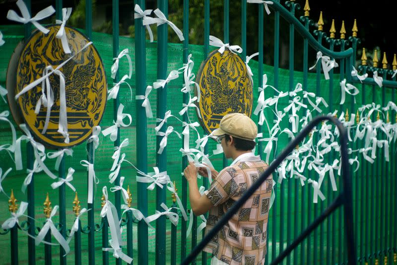 A pro-democracy protester ties white ribbons at the gate of Remand Prison in Bangkok