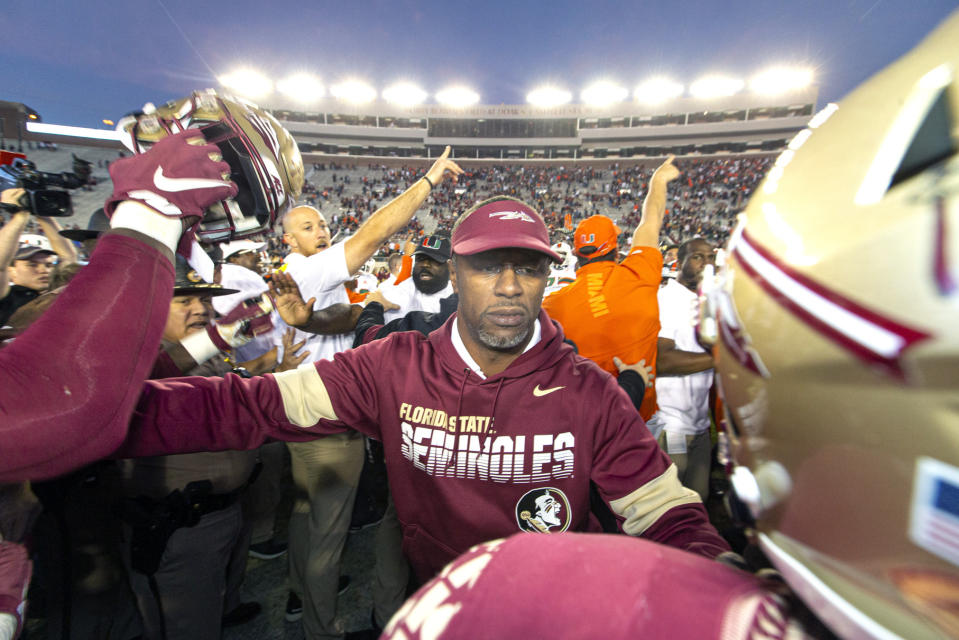 Florida State head coach Willie Taggart, center, tries to separate his team from the Miami team at midfield after Miami defeated Florida State in an NCAA college football game in Tallahassee, Fla., Saturday, Nov. 2, 2019. (AP Photo/Mark Wallheiser)