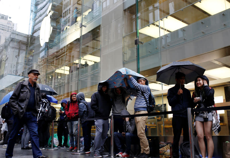 Apple customers wait in the rain outside the company's Australia's flagship store in the minutes leading up to the first sale of the iPhone 7 and Apple Watch Series 2 in Sydney, September 16, 2016. REUTERS/Steven Saphore