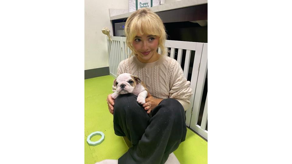 Sabrina Carpenter cuddles a puppy in her sweat pants and a beige cable knit