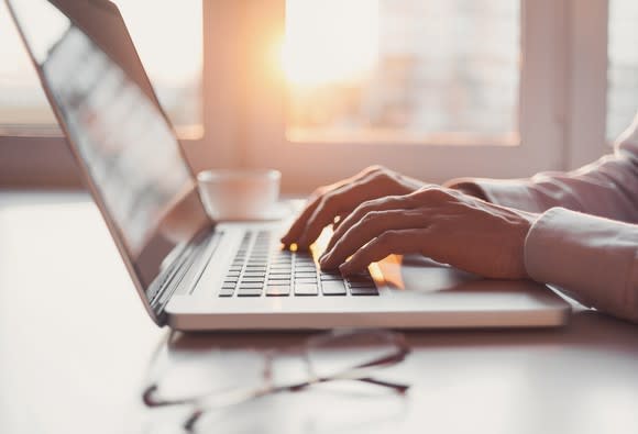 Hands typing on a laptop