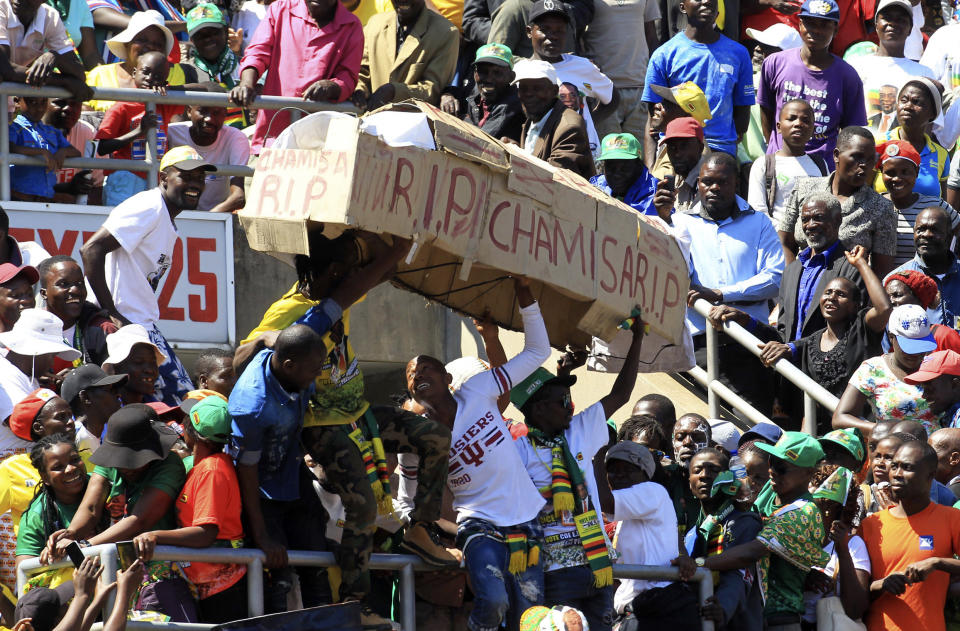 Supporters of Zimbabwean President Emmerson Mnangagwa carry a makeshift coffin bearing the name of opposition leader Nelson Chamisa during Mnangagwa's inauguration ceremony at the National Sports Stadium in Harare, Sunday, Aug. 26, 2018. Zimbabwe on Sunday inaugurated a president for the second time in nine months as a country recently jubilant over the fall of longtime leader Robert Mugabe is now largely subdued by renewed harassment of the opposition and a bitterly disputed election. (AP Photo/Tsvangirayi Mukwazhi)