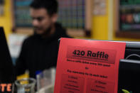 Budtender Rey Cruz rings up a customer as a 420 raffle sign is taped to a register at the Marijuana Paradise on Friday, April 19, 2024, in Portland, Ore. (AP Photo/Jenny Kane)