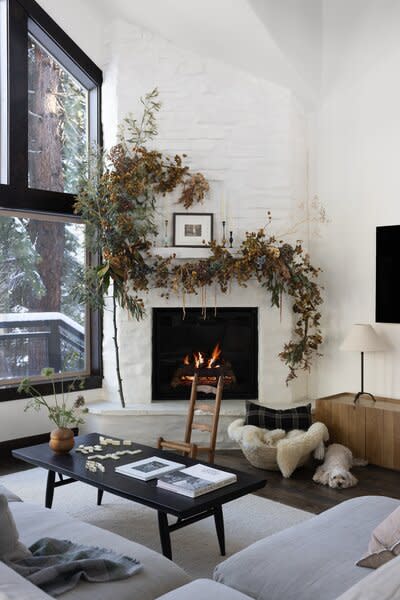 The media console and coffee table are from Sobu, while the rug is from Armadillo. A vintage chair sits near the fire.