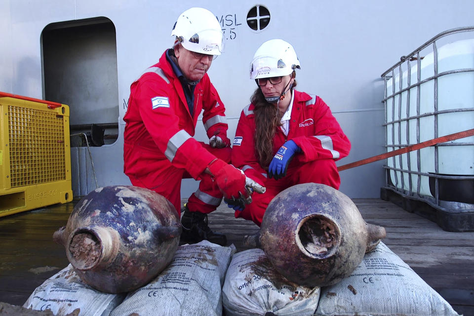 This photo released by Israel's Antiques Authority (IAA) on Thursday, June 20, 2024 shows Jacob Sharvit, left, and Dr. Karnit Bahartan, right, with the ancient jars that were carried on the world's oldest known deep-sea ship, as seen some 55.9 miles (90 kilometers off of the Israeli coastline. A company drilling for natural gas off the coast of northern Israel discovered a 3,300-year-old ship and its cargo, one of the oldest known examples of a ship sailing far from land, the Israel Antiquities Authority said on Thursday. (Emil Aladjem/ Israel Antiquities Authority via AP)