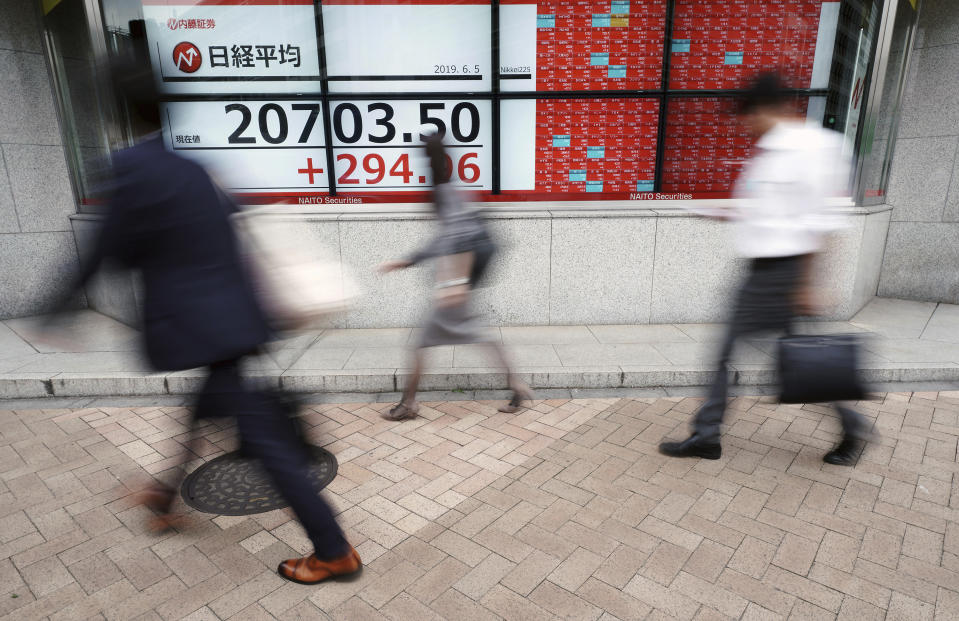 People walk past an electronic stock board showing Japan's Nikkei 225 index at a securities firm in Tokyo Wednesday, June 5, 2019. Shares surged Wednesday in Asia following a rally on Wall Street spurred by signs the Federal Reserve is ready to cut interest rates to support the U.S. economy against risks from escalating trade wars.(AP Photo/Eugene Hoshiko)