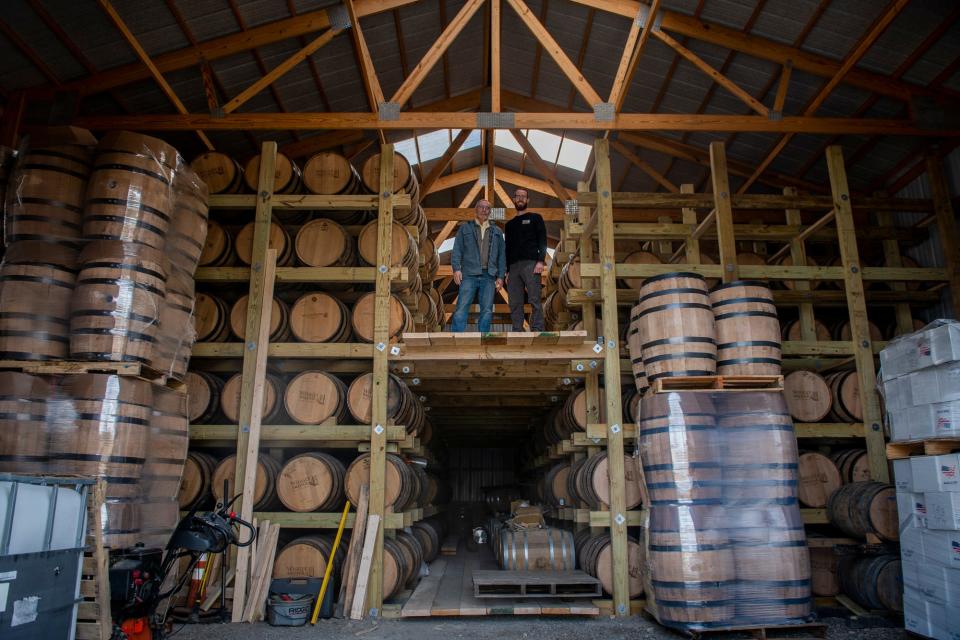 Dave Woods, left, and his son, David Woods, owners of Wiggly Bridge Distillery, pose in their barrel storage facility. They hope a build a second facility one, but Planning Board members will decide if a nearby presence of fungus will affect their approval.