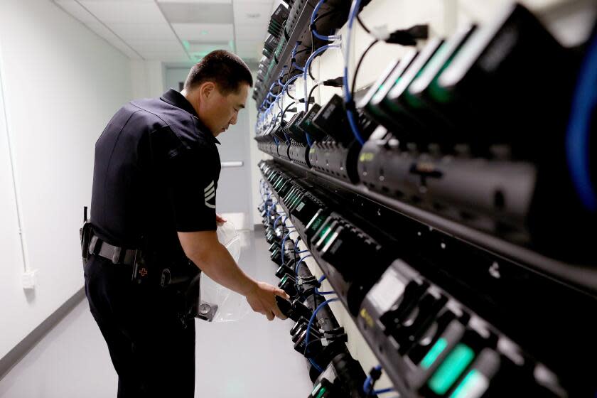 Gary Coronado  Los Angeles Times LAPD Sgt. Steve Wang loads body cameras at the Metropolitan Division. "It helps both sides of the camera," Chief Michel Moore said of the devices' impact.