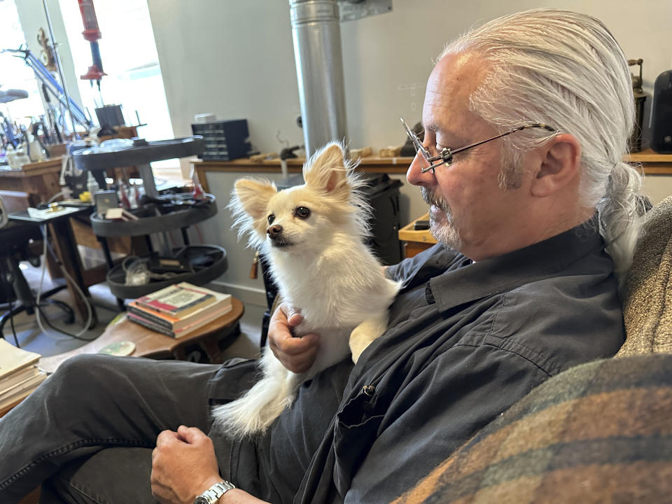 FILE - James Pelletier holds his dog, a papillon-Chihuahua mix named Lilly, at his Seattle home on June 30, 2023. Pelletier has tried new methods to help Lilly get through the stress of July Fourth fireworks, including placing sound-dulling foam over a basement window and playing loud recorded synthesizer sounds in an attempt to drown out the fireworks sounds. (AP Photo/Gene Johnson, File)