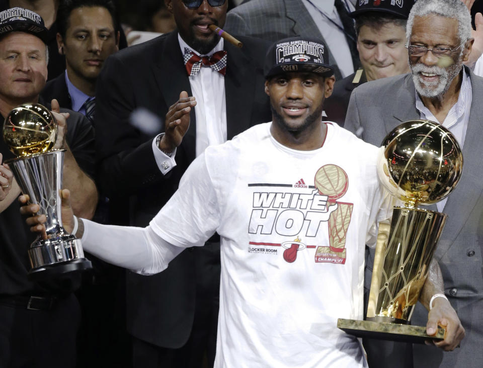 FILE - In this June 21, 2013, file photo, Miami Heat&#39;s LeBron James holds the Bill Russell NBA Finals Most Valuable Player Award in his left hand and the Larry O&#39;Brien NBA Championship Trophy after Game 7 of the NBA basketball finals in Miami. The Heat defeated the San Antonio Spurs to win their second straight NBA championship. Bill Russell is at right rear. Miami changed James for the better. He came back to Ohio more confident, more determined--a two-time NBA champion. He&#39;s now drawing on his experiences to make a run at another title. (AP Photo/Wilfredo Lee, File)