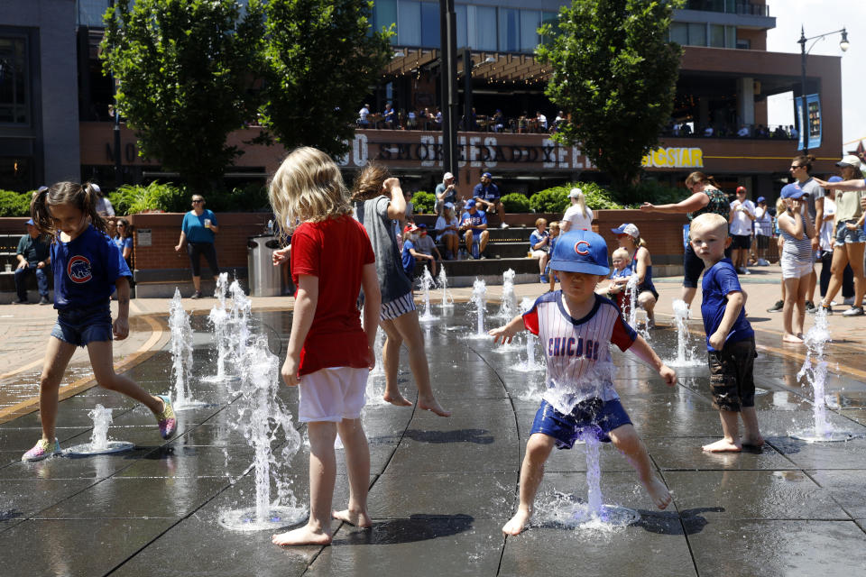 Kids play around a water fountain outside of Chicago's Wrigley Field before a baseball game, Friday, June 11, 2021, as Chicago and rest of Illinois fully reopens ending an over a year-long COVID-19 restrictions. (AP Photo/Shafkat Anowar)