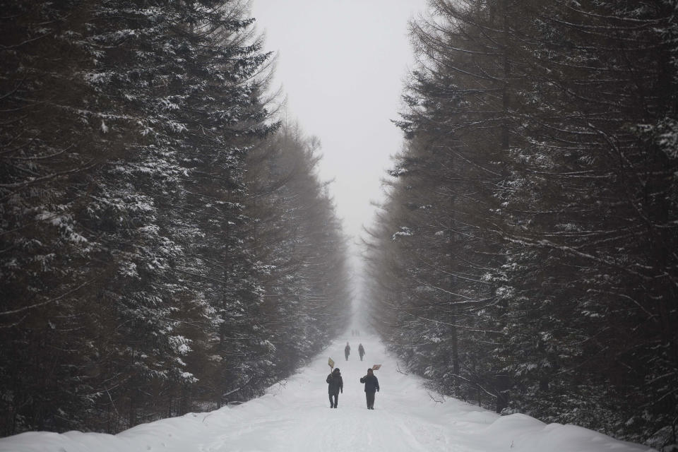 FILE - In this April 3, 2012, file photo, North Korean women carry wooden snow shovels as they make their way along a snowy road at the foot of Mount Paektu near Samjiyon, North Korea. There is no more sacred a place in North Korea than Mount Paektu. The still active volcano, site of one the most violent eruptions in history, is considered to be the spiritual epicenter of the North Korean revolution. (AP Photo/David Guttenfelder, File)