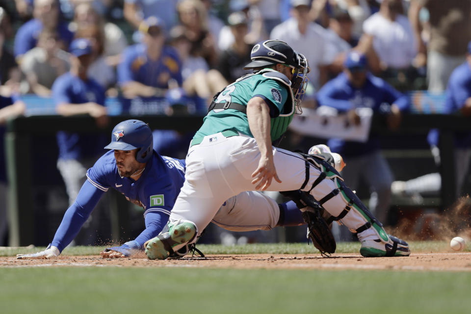 Toronto Blue Jays' George Springer scores before the tag from Seattle Mariners catcher Mitch Garver during the fifth inning in a baseball game, Saturday, July 6, 2024, in Seattle. (AP Photo/John Froschauer)