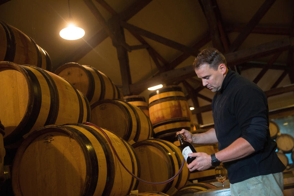 Friedrich Wilhelm Becker syphons pinot noir from a barrel during the Oct. 4 tasting.