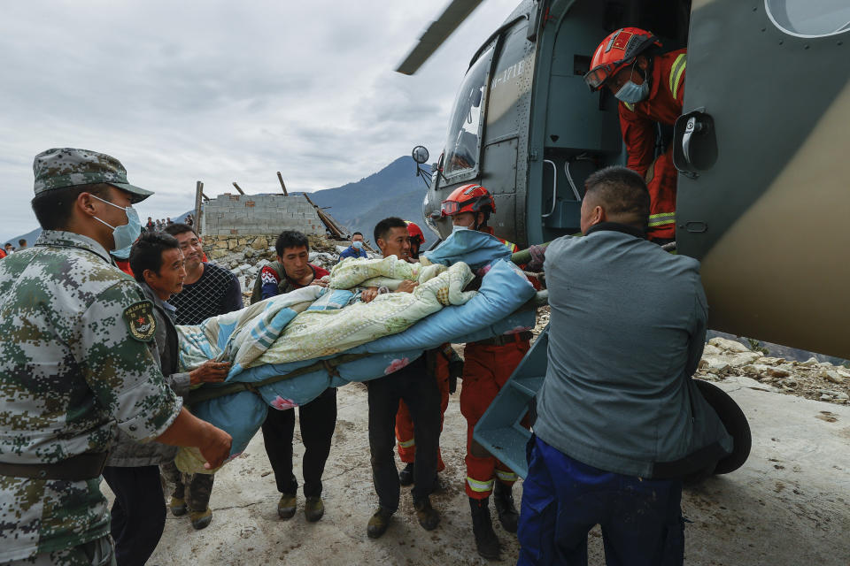 In this photo released by Xinhua News Agency, rescuers using helicopter to transfer injured villagers following an earthquake in Detuo Town of Luding County, southwest China's Sichuan Province Tuesday, Sept. 6, 2022. Authorities in southwestern China's Chengdu have maintained strict COVID-19 lockdown measures on the city of 21 million despite a major earthquake that killed dozens of people in outlying areas. (Shen Bohan/Xinhua via AP)