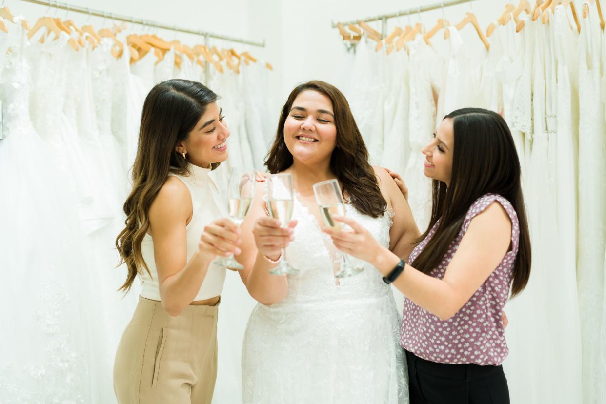 Cheerful bridesmaids and obese future bride making a toast while celebrating with champagne at the bridal shop