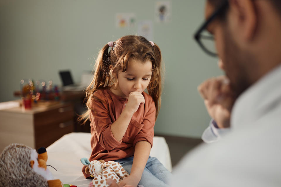 Cute little girl coughing during a medical exam with her pediatrician in hospital.