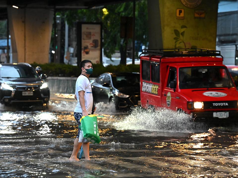 A man walks along a flooded street in Manila on October 29, 2022, following heavy rain brought by Tropical Storm Nalgae.