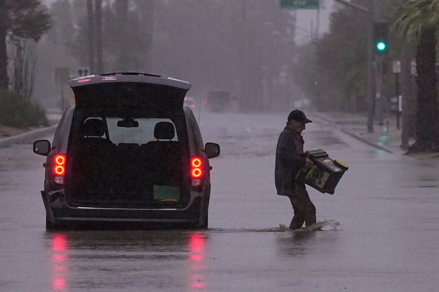 A motorist removes belongings from his vehicle after becoming stuck in a flooded street, Sunday, Aug. 20, 2023, in Palm Desert, Calif. Forecasters said Tropical Storm Hilary was the first tropical storm to hit Southern California in 84 years, bringing the potential for flash floods, mudslides, isolated tornadoes, high winds and power outages. (AP Photo/Mark J. Terrill)