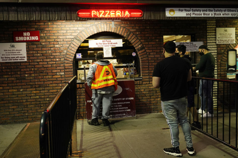 People line up to order take-out pizzas at L&B Spumoni Gardens, Sunday, Oct. 4, 2020, in the Brooklyn borough of New York. The restaurant's indoor dining is closed due to the limitations of serving at 25% capacity, and is also being renovated. But the large outdoor seating area was busy at dinner time Sunday. Since it's in a New York city zip code experiencing a rise in the number of coronavirus cases, the restaurant may be forced to close all but its takeout service and delivery service. (AP Photo/Kathy Willens)