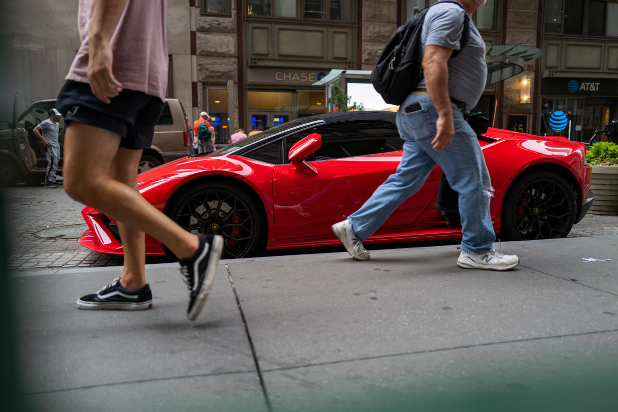 NEW YORK, NEW YORK - JULY 18: People walk by a Lamborghini car along Wall Street in the Financial District of Manhattan on July 18, 2022 in New York City. Global markets continue to be volatile as inflation in the United States hit a 40-year high while fuel prices have started to decline. Despite the uncertainty, consumers continue to spend as retail sales rose 1% between May and June.