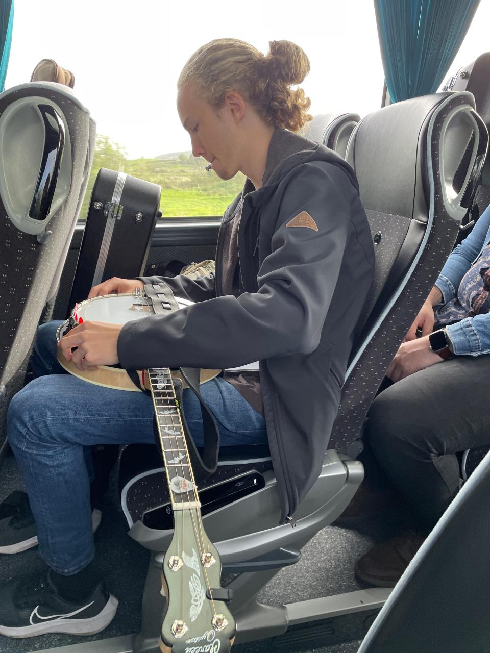 Flynn Whitmore tunes his banjo while on a bus.