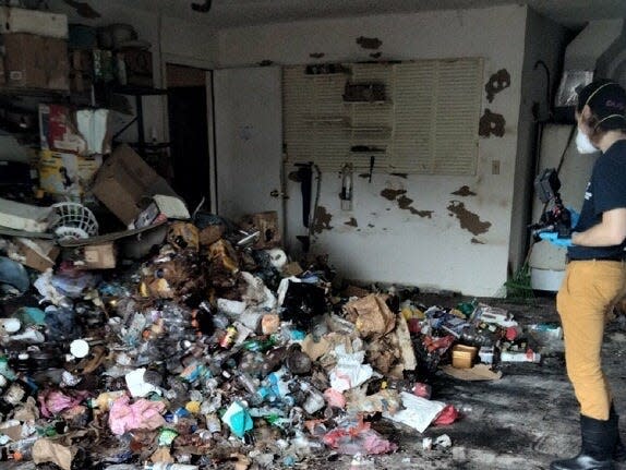 A garage with stripped down floors and a pile of trash.