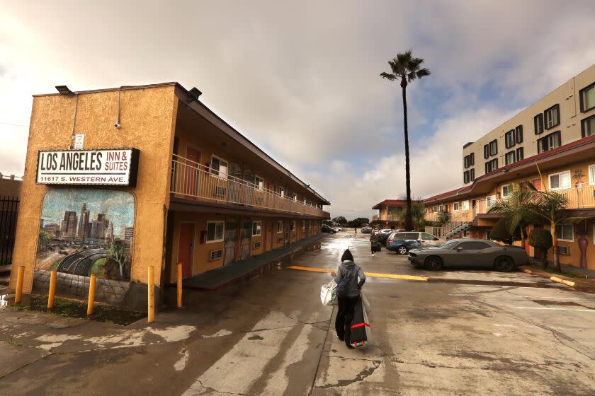 LOS ANGELES, CA - JANUARY 5, 2023 - - Iyana Woods, 43, carries her belongings after arriving by bus to the Los Angeles Inn and Suites as part of the Inside Safe initiative in Los Angeles on January 5, 2023. Those transported to the hotel had been living homeless on Hampton Dr. In Venice and were offered housing by workers with the St. Joseph's Center and LAHSA as part of the Inside Safe program. (Genaro Molina / Los Angeles Times)