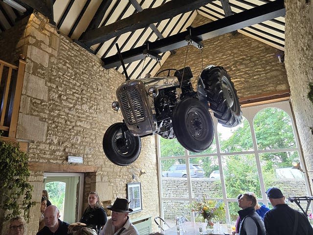 A vintage tractor hangs from the rafters of the pub building