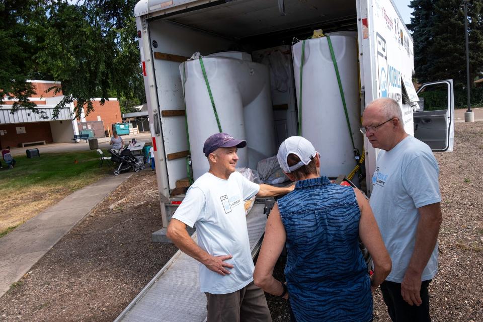 Woody Carlson talks with other volunteers in front of Homeward Alliance's mobile laundry truck during a drop-off at the Fullana Learning Center on Tuesday, July 17, 2024, in Fort Collins, Colo. The laundry truck was damaged in a crash nearly five months ago was recently repaired.