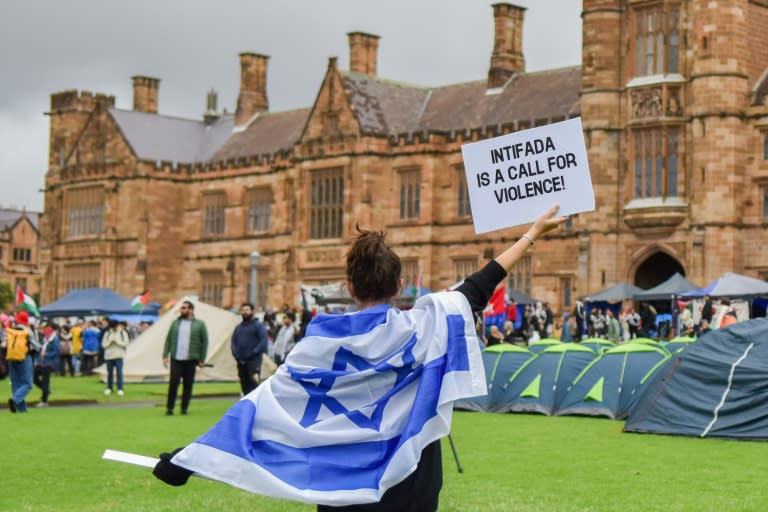 A member of the Australian Israeli community holds up a sign at the Palestinian Protest Campsite where members of the Australian Palestinian community can be seen protesting in the background at University of Sydney in Sydney on May 3, 2024. (Ayush Kumar)